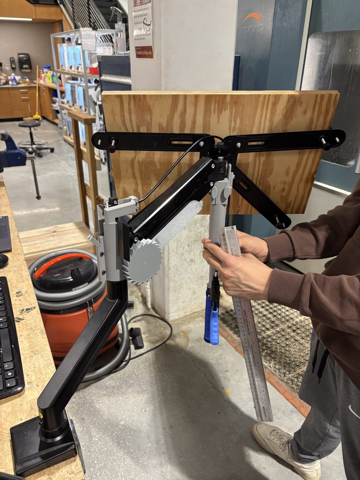 CALM on a commercial monitor arm: the ratcheting gear at the joint, cable running down to the bike brake lever on the telescoping handle.